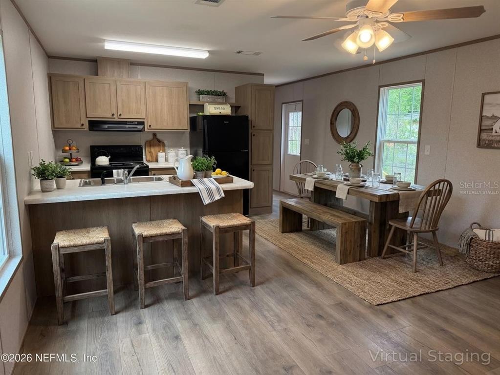 A kitchen and dining area featuring wood-look flooring, light wood cabinets, and a breakfast bar — 213 MILTON AVENUE, INTERLACHEN, FL