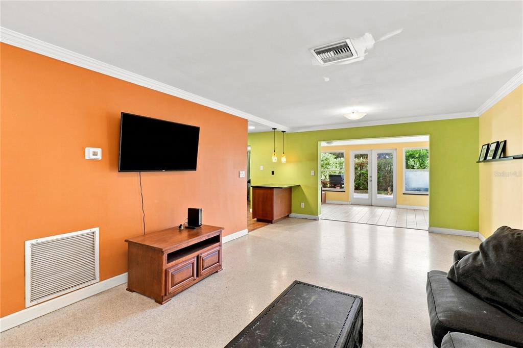 A living room features orange and lime green walls, a television, and a tiled floor — 1070 6TH AVENUE NE, LARGO, FL