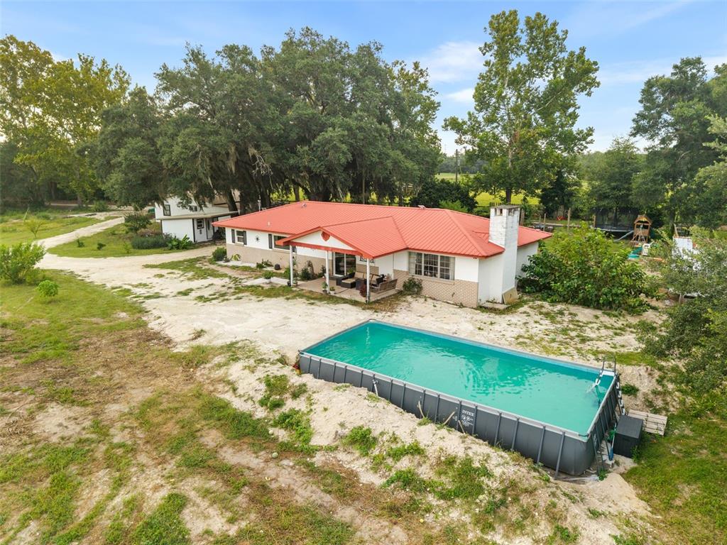 An aerial view of a single-story house with a red metal roof and an above-ground pool — 1750 SW 17TH TERRACE, BELL, FL