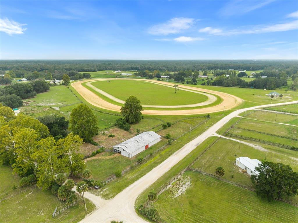 An aerial view of a rural property featuring a dirt horse track and a barn — 1750 SW 17TH TERRACE, BELL, FL