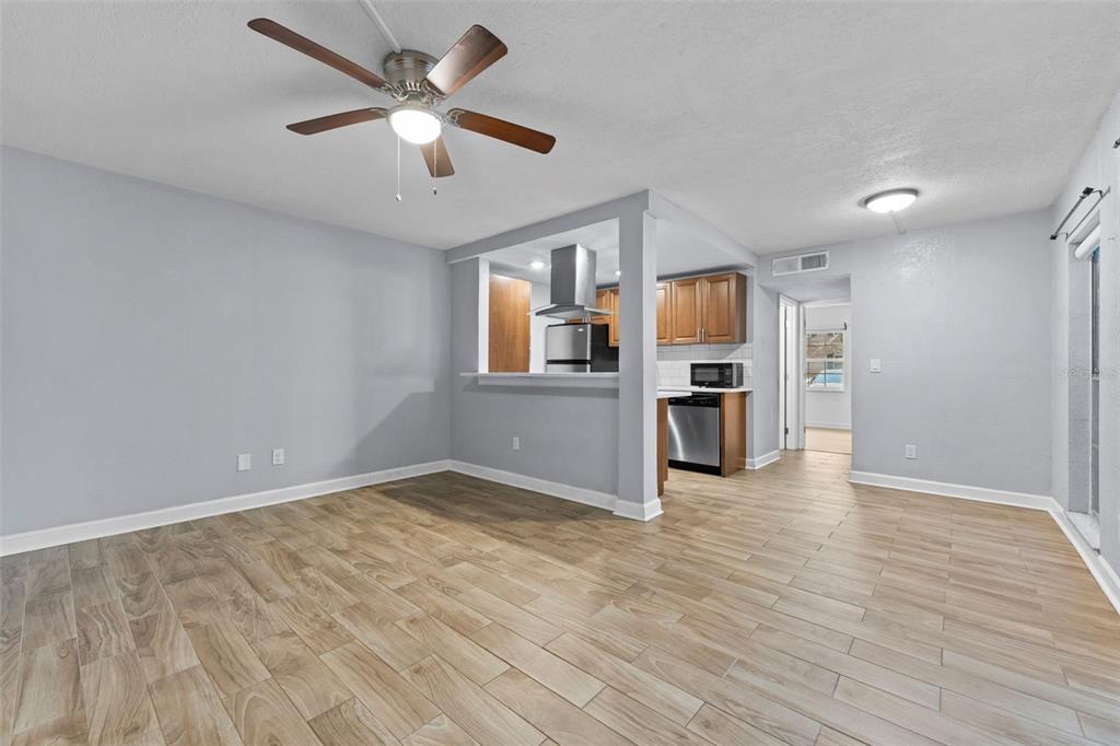 An open-concept living area features light gray walls, wood-look tile flooring, and a pass-through kitchen — 4611 W NORTH B STREET UNIT 123, TAMPA, FL