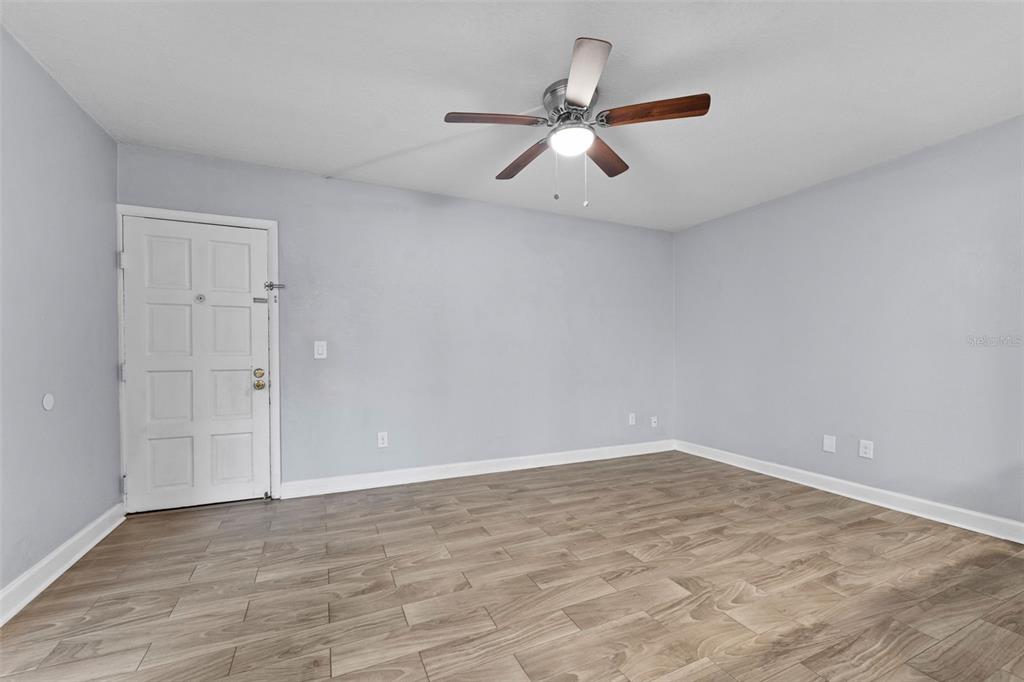 An empty room features light gray walls, wood-look tile flooring, and a ceiling fan — 4611 W NORTH B STREET UNIT 123, TAMPA, FL