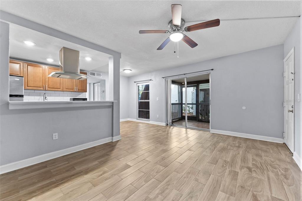 A living room with light wood-look tile flooring, a ceiling fan, and an adjacent kitchen — 4611 W NORTH B STREET UNIT 123, TAMPA, FL