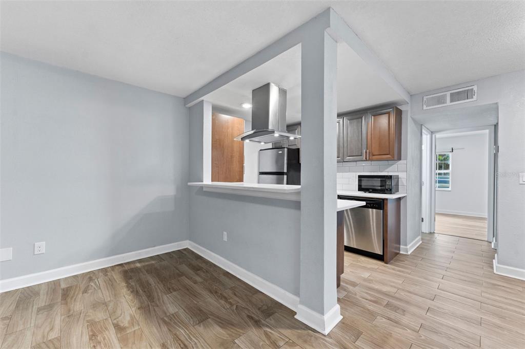 A dining area opens to a kitchen featuring stainless steel appliances and dark wood cabinets — 4611 W NORTH B STREET UNIT 123, TAMPA, FL
