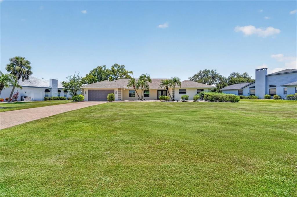 A single-story house with a large lawn, palm trees, and a paved driveway — 3504 WILDERNESS BOULEVARD W, PARRISH, FL