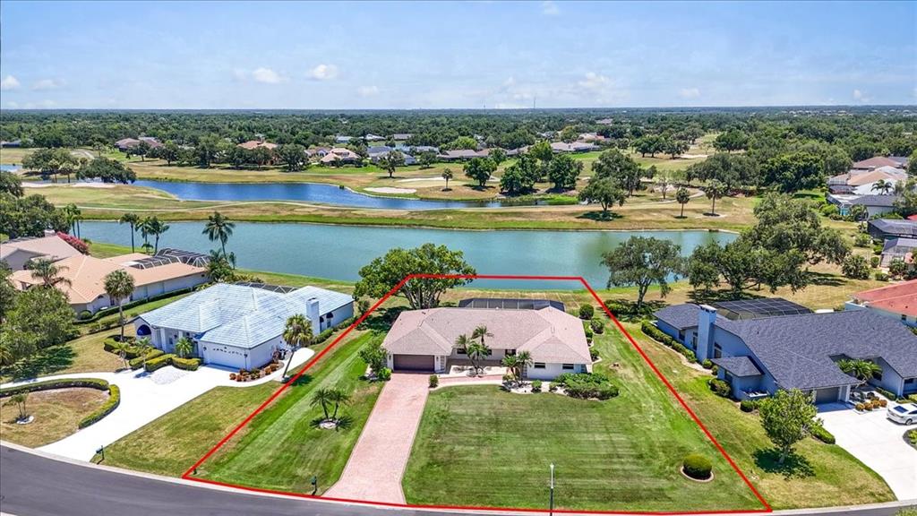 An aerial view shows a single-story house with a large lawn and a lake behind — 3504 WILDERNESS BOULEVARD W, PARRISH, FL