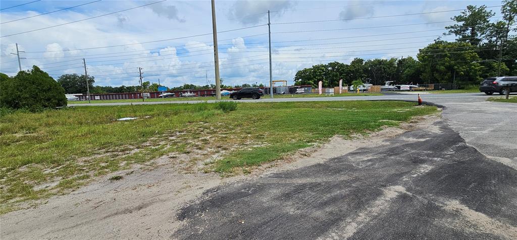 A grassy, undeveloped lot sits next to a paved road with power lines overhead — COUNTY ROAD 44, LEESBURG, FL