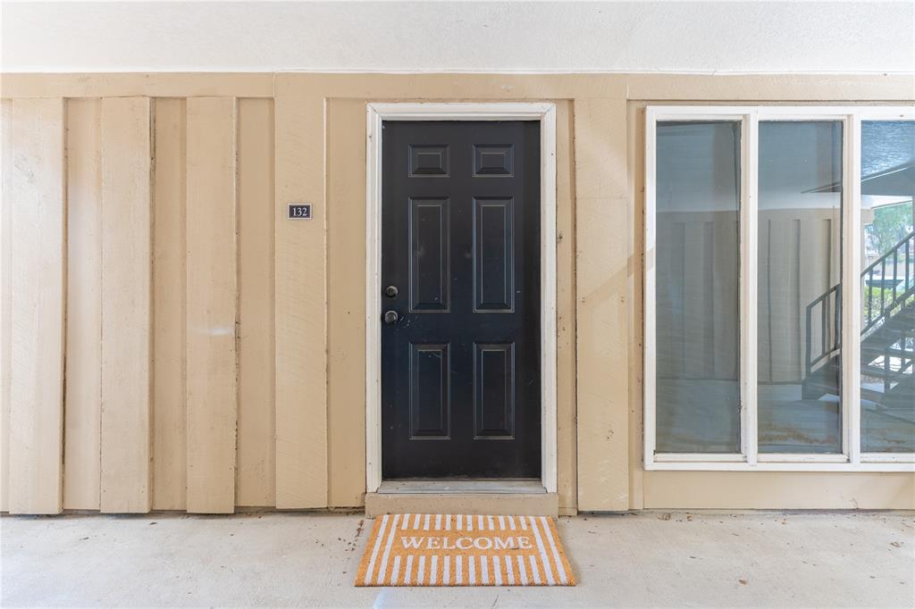 A black front door with the number 132 is centered on a tan exterior wall — 507 NW 39TH ROAD UNIT 132, GAINESVILLE, FL