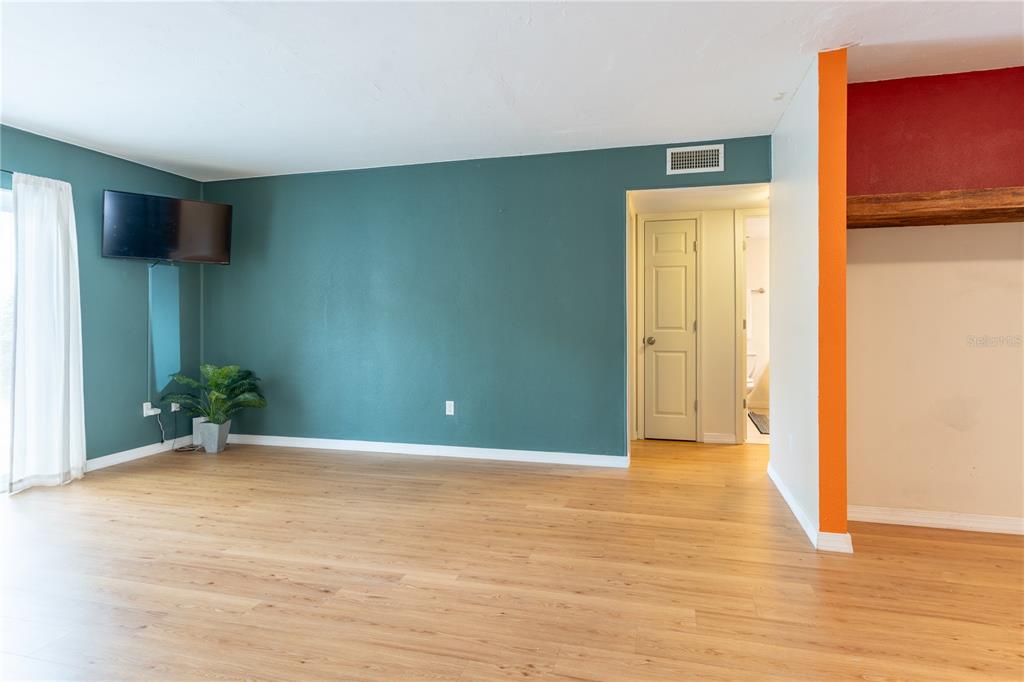 A living room features teal walls, light wood-look flooring, and an orange accent wall — 507 NW 39TH ROAD UNIT 132, GAINESVILLE, FL