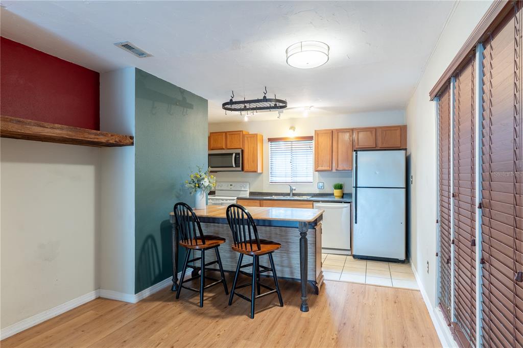 A kitchen features wood cabinets, stainless steel appliances, a center island, and wood-look flooring — 507 NW 39TH ROAD UNIT 132, GAINESVILLE, FL