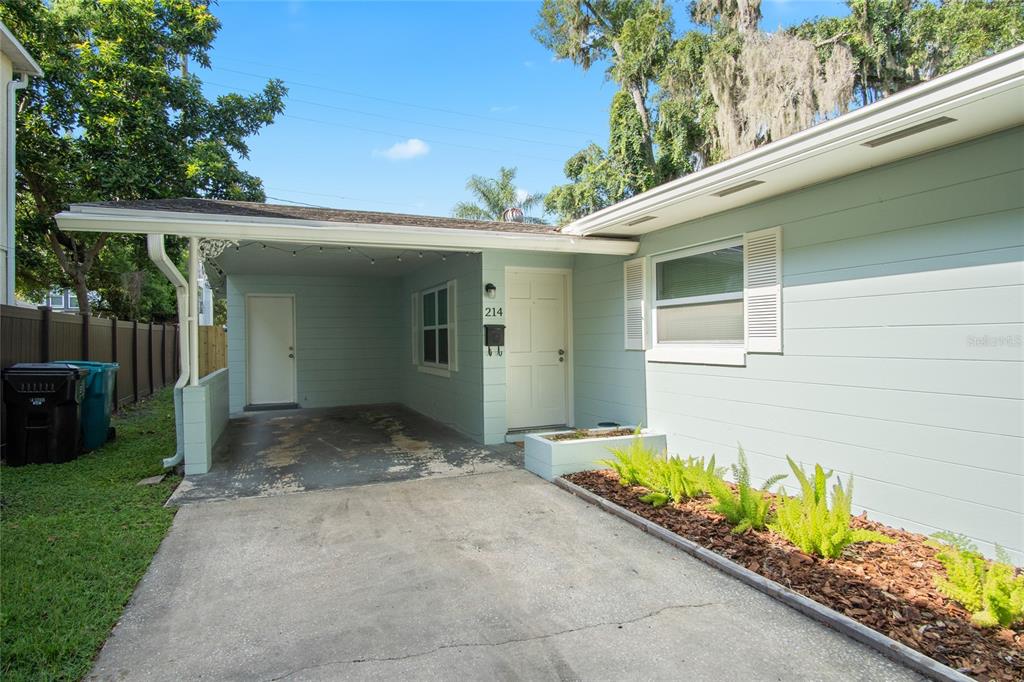 A light blue house exterior features a concrete driveway, a carport, and a small garden bed — 212 E HARVARD STREET, ORLANDO, FL