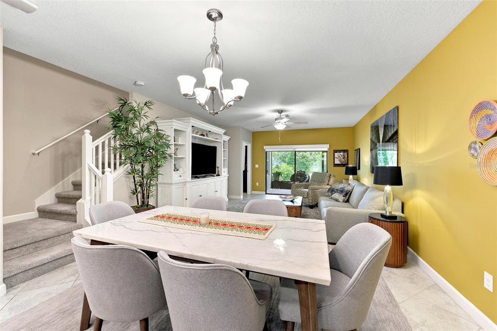 A dining area with a marble table leads into a living room with yellow walls — 5305 STOIC VALE DRIVE, WIMAUMA, FL