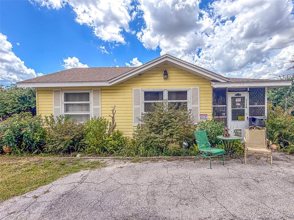 A yellow, single-story house with a gabled roof, white shutters, and a paved driveway — 1120 S SCENIC HIGHWAY, LAKE WALES, FL