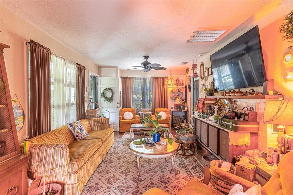 A living room features a striped sofa, two orange armchairs, a patterned rug, and television — 1120 S SCENIC HIGHWAY, LAKE WALES, FL