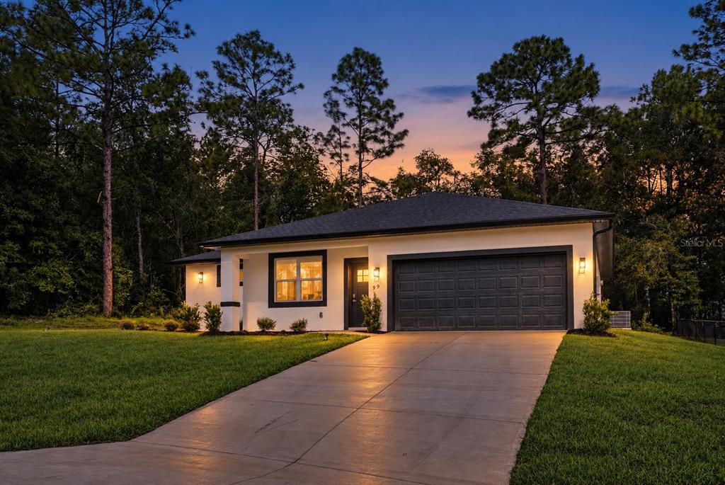 A modern kitchen features white cabinetry, stainless steel appliances, and a quartz-topped island with seating — 99 W GOLDCOAST PLACE, DUNNELLON, FL