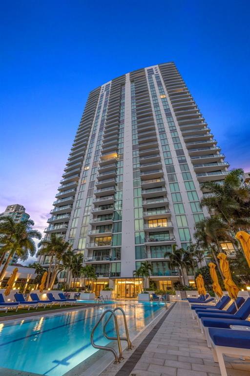 A living room with a beige sectional, blue armchair, and floor-to-ceiling windows overlooking a marina — 100 1ST AVENUE N UNIT 1603, ST PETERSBURG, FL
