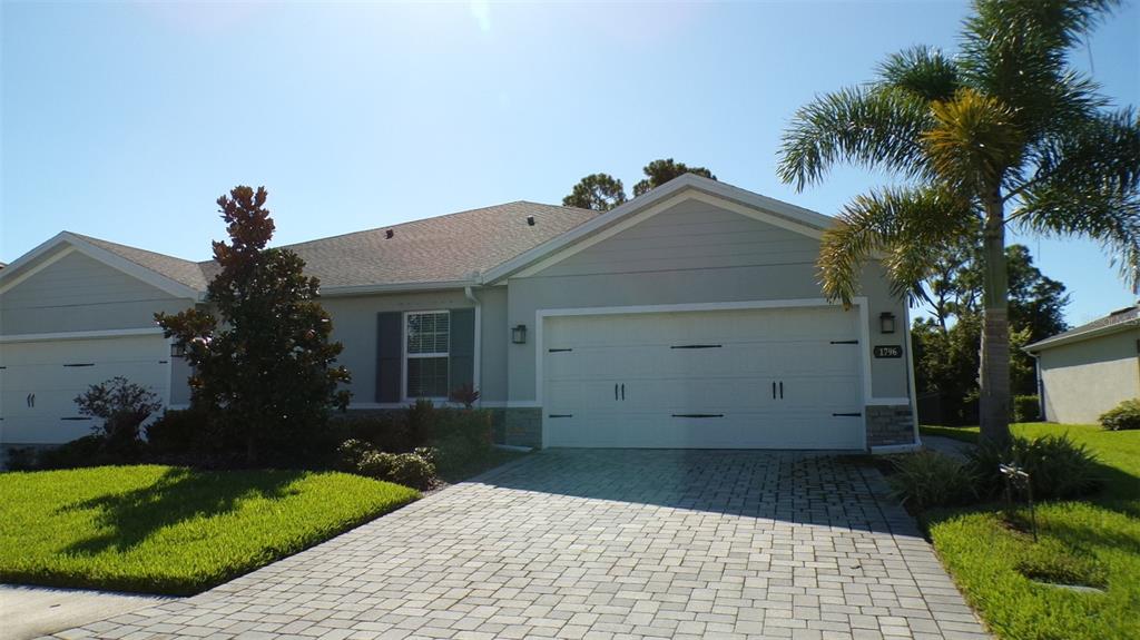 A single-story house with a paved driveway, white garage door, and a palm tree — 1796 W PALMS DRIVE, PORT CHARLOTTE, FL