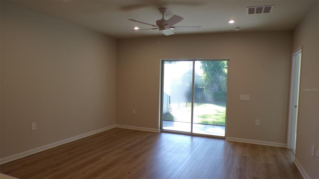 A room with light wood-look flooring, a ceiling fan, and a sliding glass door — 1796 W PALMS DRIVE, PORT CHARLOTTE, FL
