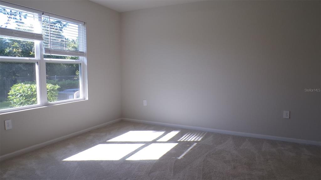 An empty bedroom features beige walls, light-colored carpeting, and a window with white blinds — 1796 W PALMS DRIVE, PORT CHARLOTTE, FL