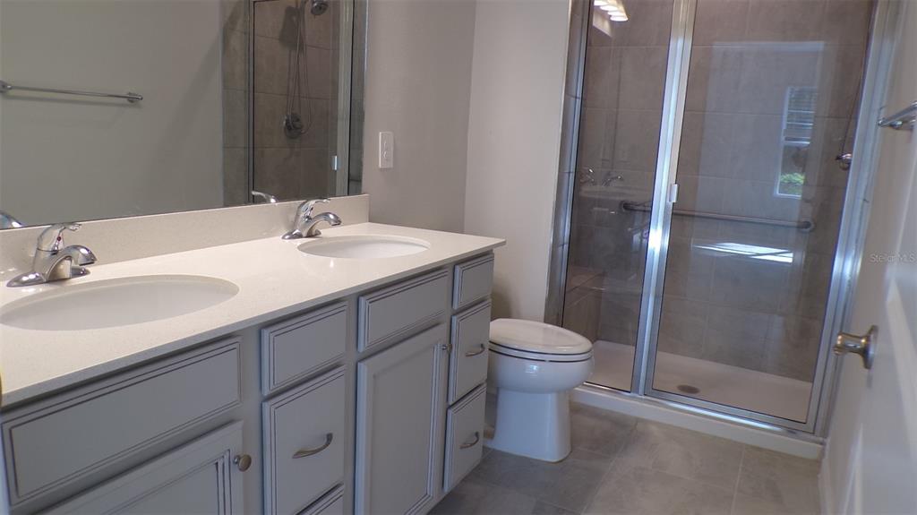 A bathroom with a double vanity, gray cabinets, a white countertop, and a glass shower — 1796 W PALMS DRIVE, PORT CHARLOTTE, FL