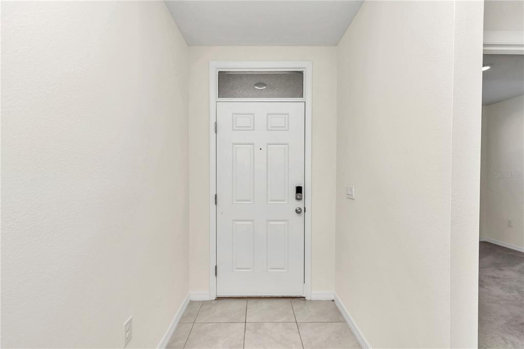 An entryway features a white front door with a transom window and tiled flooring — 27 HICKORY COURSE LANE, OCALA, FL