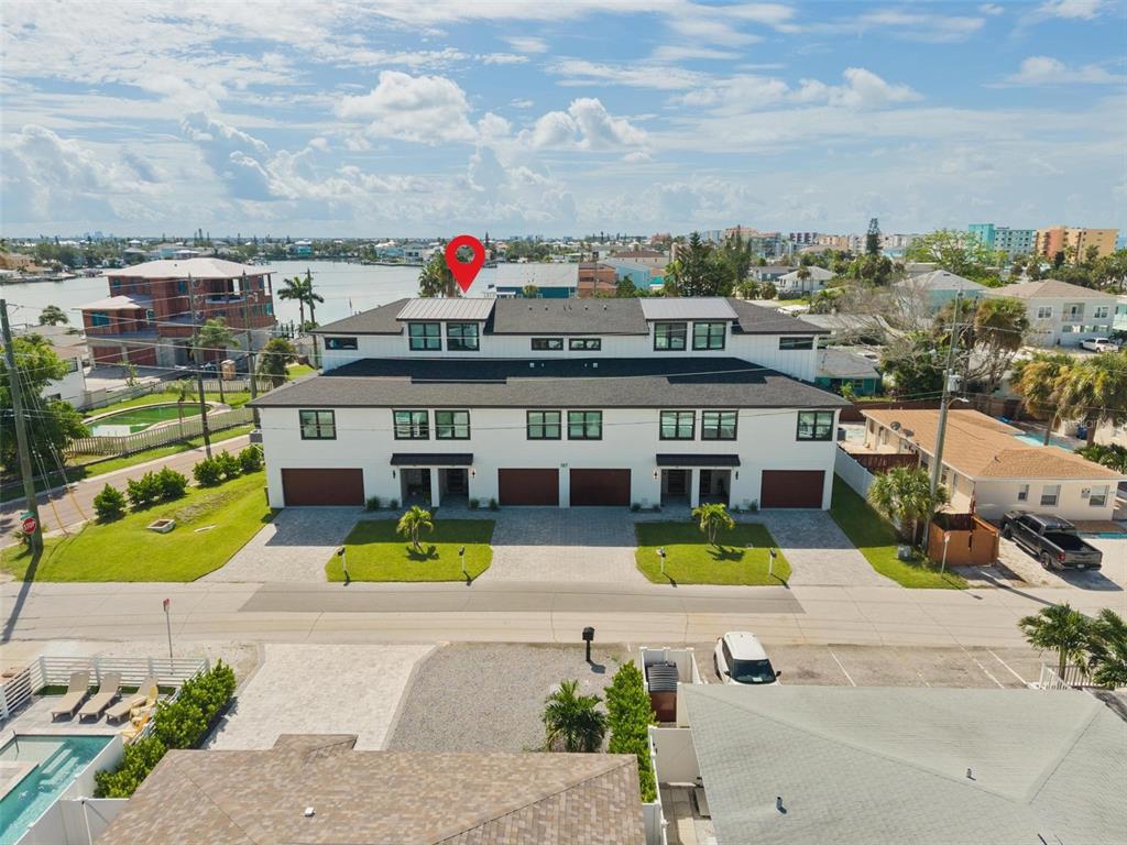 An aerial view shows a modern multi-unit townhouse with a dark roof and white siding — 187 145TH AVENUE E UNIT 3, MADEIRA BEACH, FL