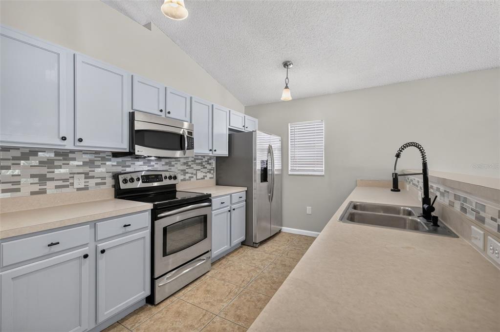 A kitchen with light gray cabinets, stainless steel appliances, and a tiled floor — 2225 SANDRIDGE CIRCLE, EUSTIS, FL