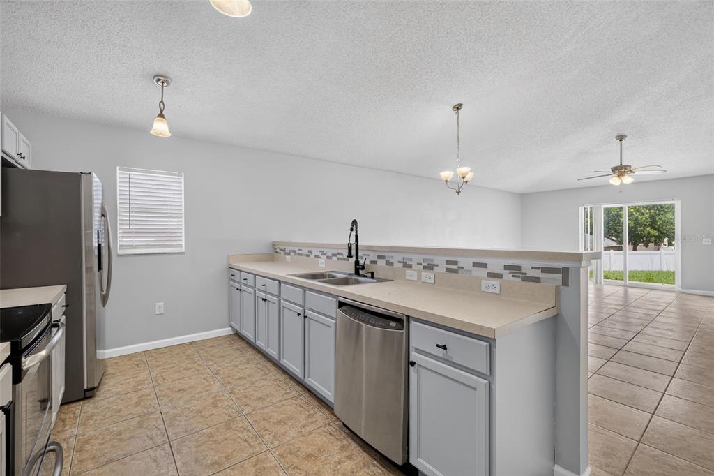 A kitchen features light gray cabinets, stainless steel appliances, and a tiled backsplash — 2225 SANDRIDGE CIRCLE, EUSTIS, FL