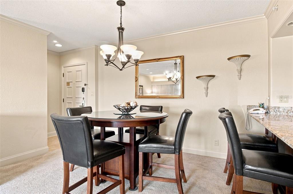 A dining area features a round wooden table, four black chairs, and a chandelier — 36750 US HIGHWAY 19 N UNIT 04-130, PALM HARBOR, FL