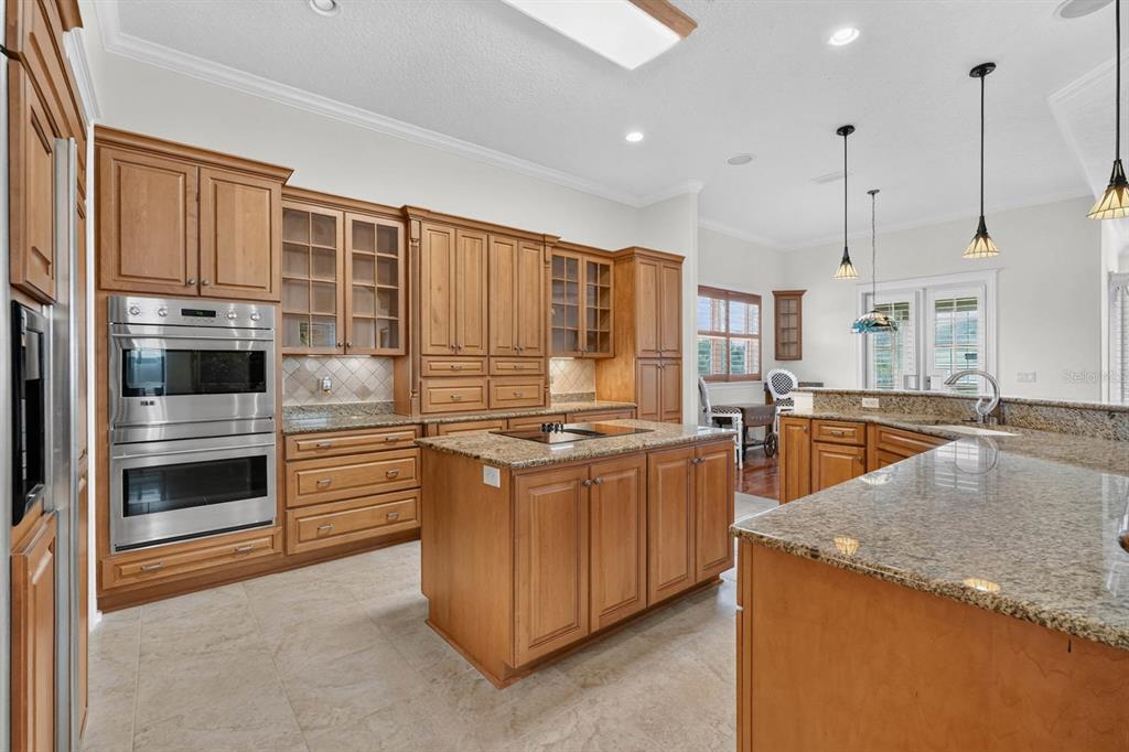 A kitchen with wood cabinets, granite countertops, a center island, and stainless steel double ovens — 303 YACHT HARBOR DRIVE, PALM COAST, FL