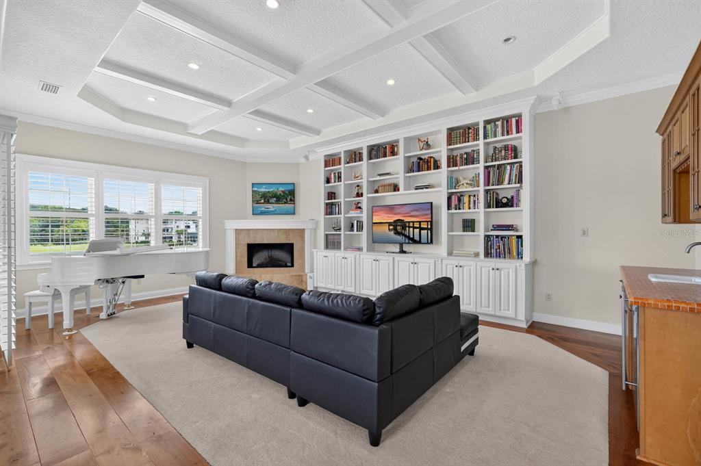 A living room features a white grand piano, a fireplace, built-in bookshelves, and a sectional sofa — 303 YACHT HARBOR DRIVE, PALM COAST, FL