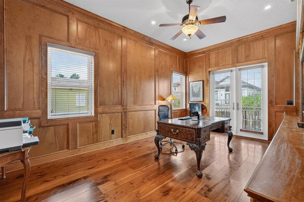 A home office features wood-paneled walls, hardwood floors, a desk, and a ceiling fan — 303 YACHT HARBOR DRIVE, PALM COAST, FL