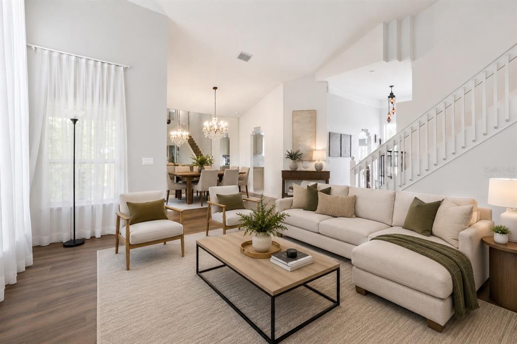 A bright living room features a sectional sofa, two armchairs, a coffee table, and stairs — 3408 IDLEGROVE COURT, ORLANDO, FL