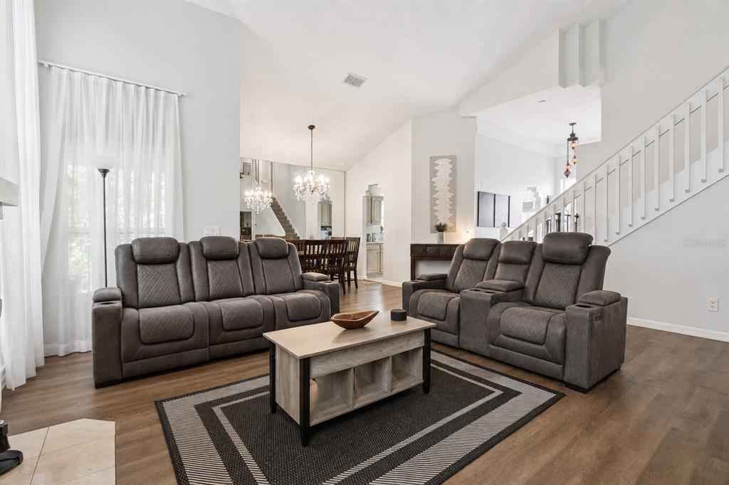 A living room features two gray reclining sofas, a coffee table, and a staircase — 3408 IDLEGROVE COURT, ORLANDO, FL