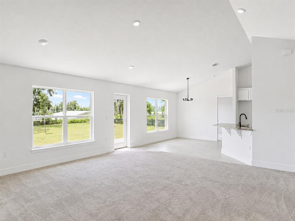 A kitchen features white cabinets, granite countertops, a black faucet, and stainless steel appliances — 1684 ANN ROSE WAY, LEESBURG, FL