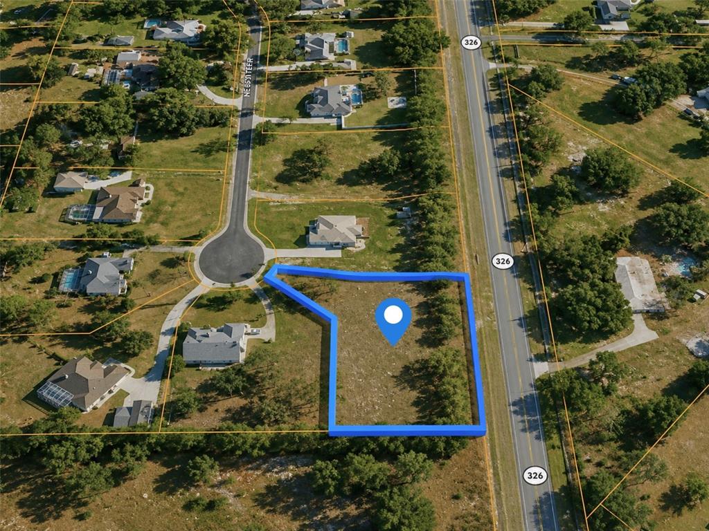 An aerial view shows a vacant, rectangular lot highlighted in blue next to a highway — X, SILVER SPRINGS, FL