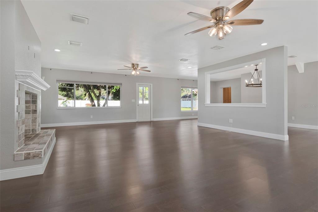 A spacious living room features dark hardwood floors, a large sectional sofa, and a fireplace — 712 S OAKWOOD AVENUE, BRANDON, FL