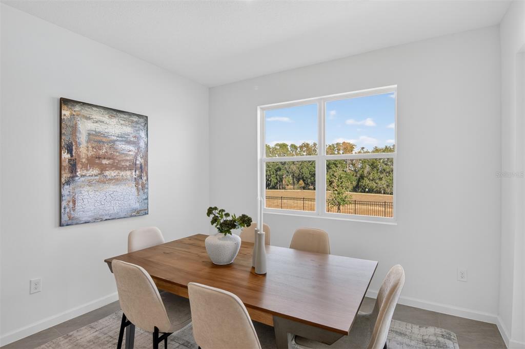 A dining room features a wooden table, six chairs, abstract wall art, and a large window — 336 FREE RANGE DRIVE, GROVELAND, FL