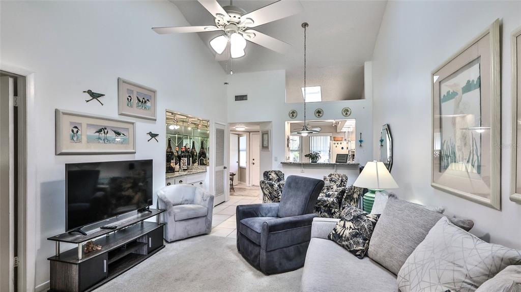 A living room features a vaulted ceiling, a ceiling fan, a television, and a bar area — 932 MEADOW VIEW DRIVE UNIT C, PORT ORANGE, FL