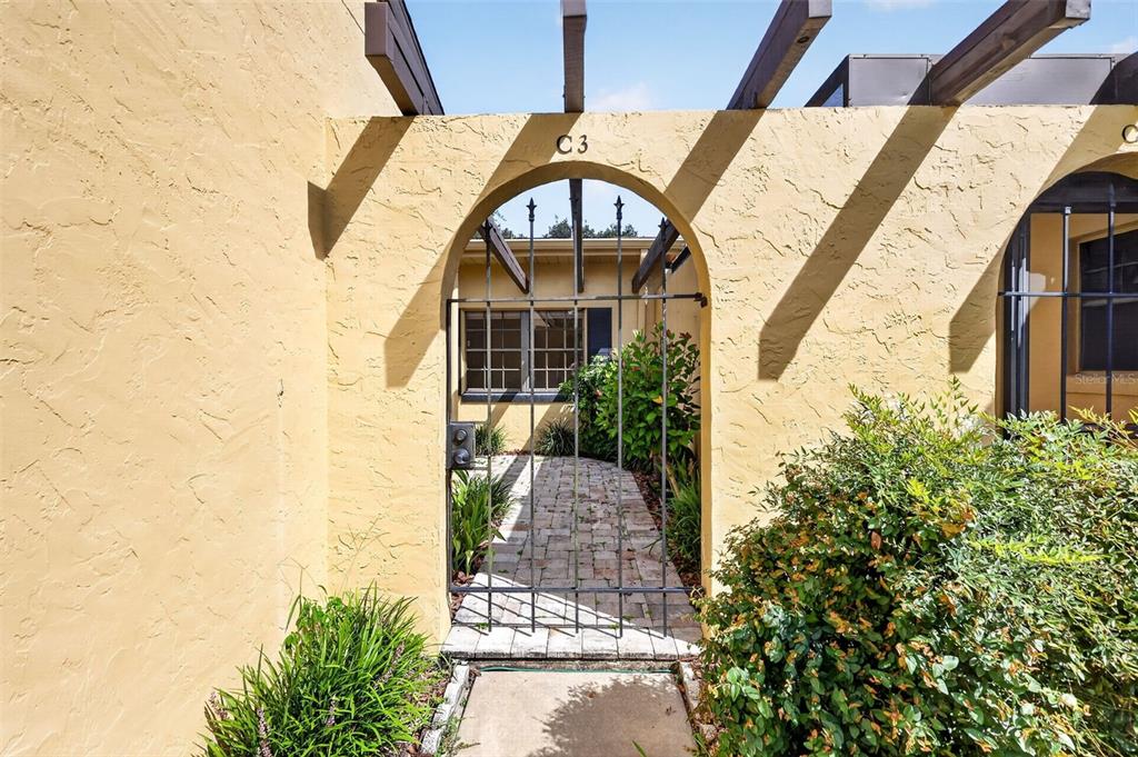 A gated entrance leads to a paved walkway and a yellow stucco building exterior — 1111 LAKESHORE DRIVE UNIT C3, EUSTIS, FL