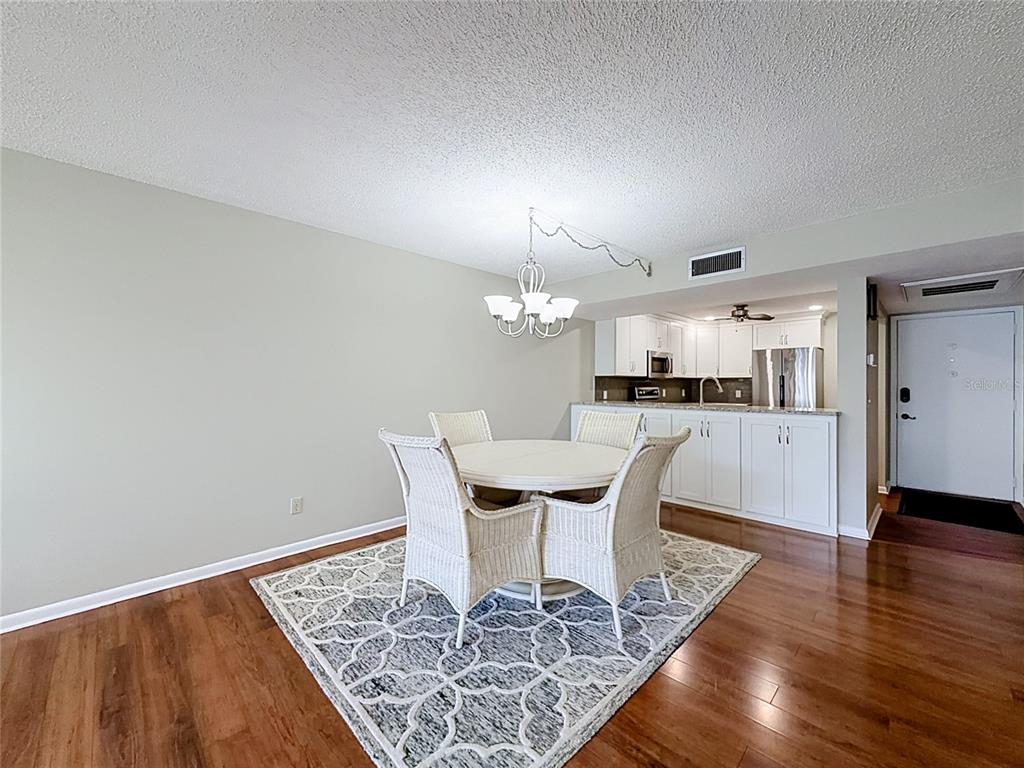 A dining area with a round table, wicker chairs, and a patterned rug near a kitchen — 11945 143RD STREET UNIT 7322, LARGO, FL