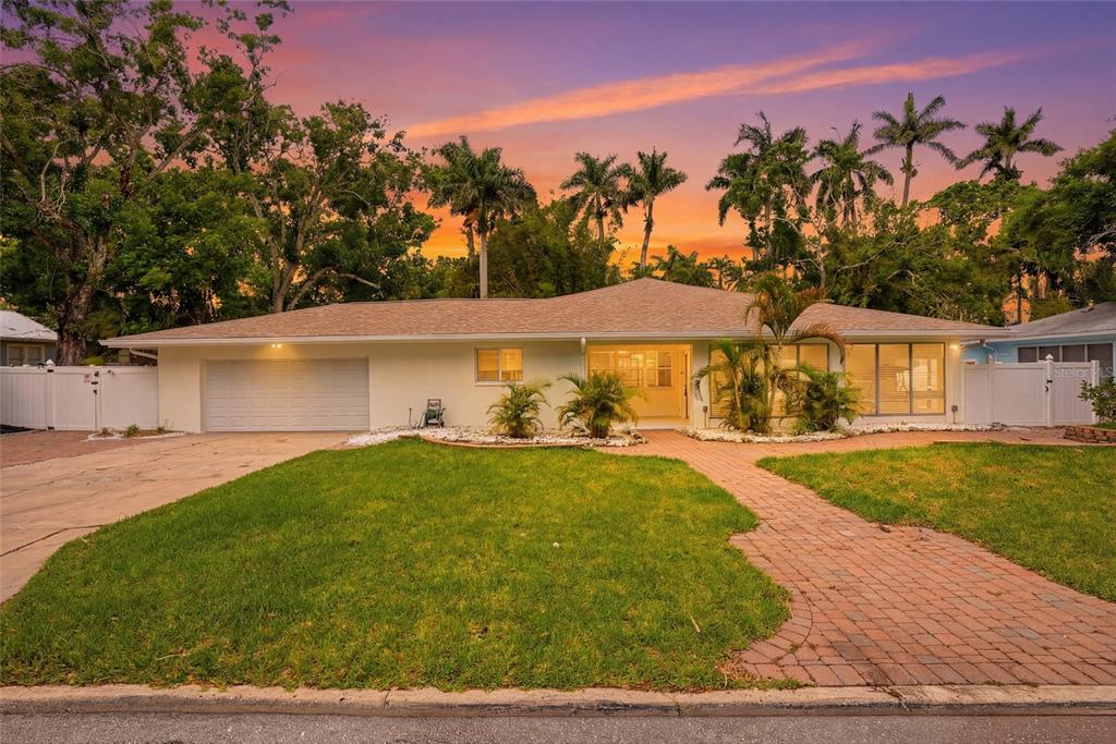 A single-story house with a white exterior, attached garage, and brick walkway at sunset — 2004 VIRGINIA DRIVE, BRADENTON, FL