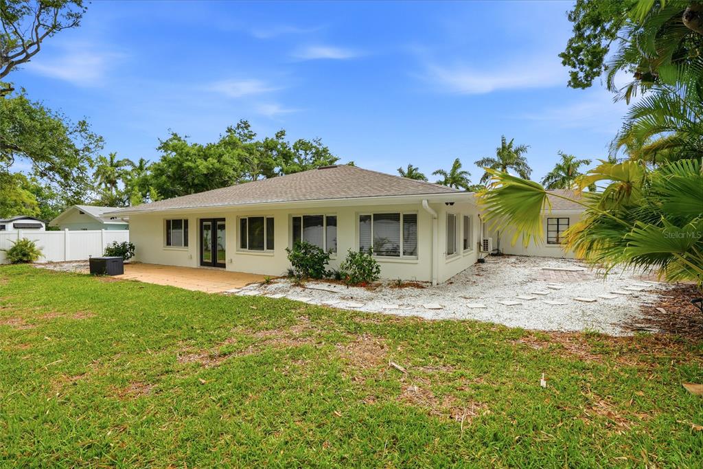 The exterior of a single-story house features a white stucco facade, a patio, and landscaping — 2004 VIRGINIA DRIVE, BRADENTON, FL