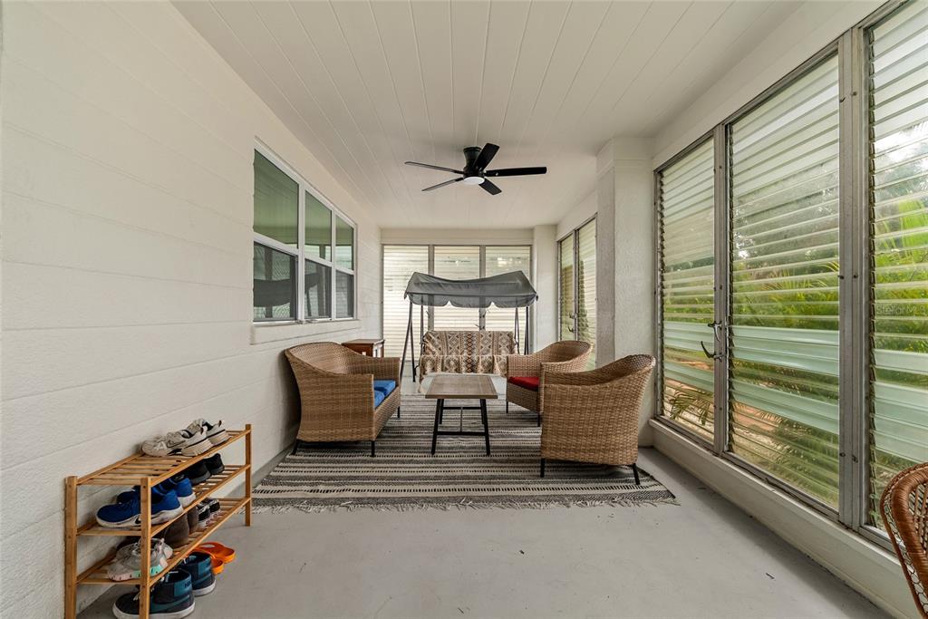 A covered patio features wicker furniture, a swing, a shoe rack, and large glass windows — 2004 VIRGINIA DRIVE, BRADENTON, FL