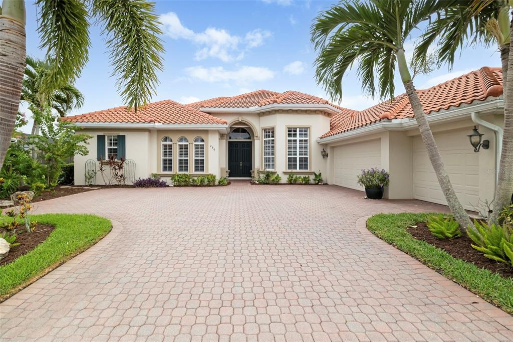 A single-story house with a tiled roof, arched entryway, and a paved circular driveway — 286 PESARO DRIVE, NOKOMIS, FL
