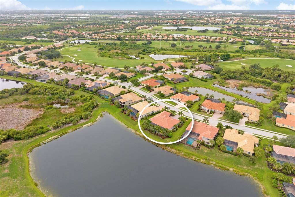 An aerial view shows a residential house with a tile roof situated beside a lake — 286 PESARO DRIVE, NOKOMIS, FL