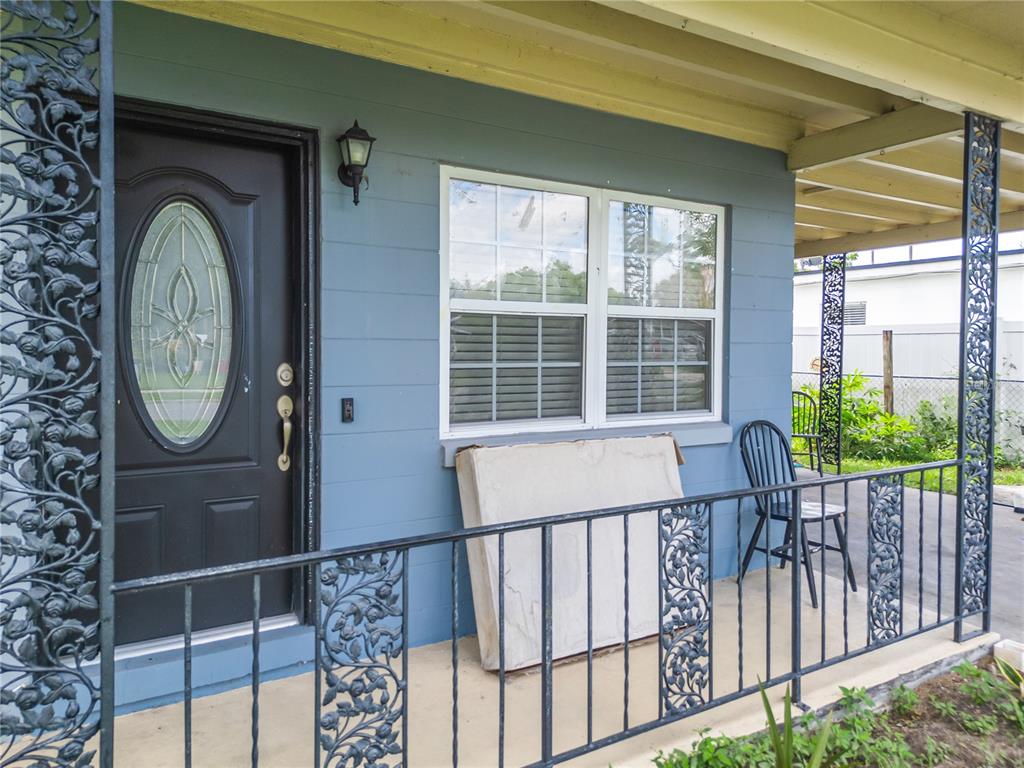 A blue house exterior features a front porch with decorative iron railings and a door — 6017 CANDLEWOOD LANE, ORLANDO, FL