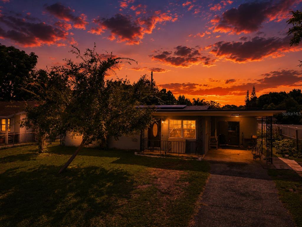 A single-story house with a driveway and a tree under a vibrant sunset sky — 6017 CANDLEWOOD LANE, ORLANDO, FL