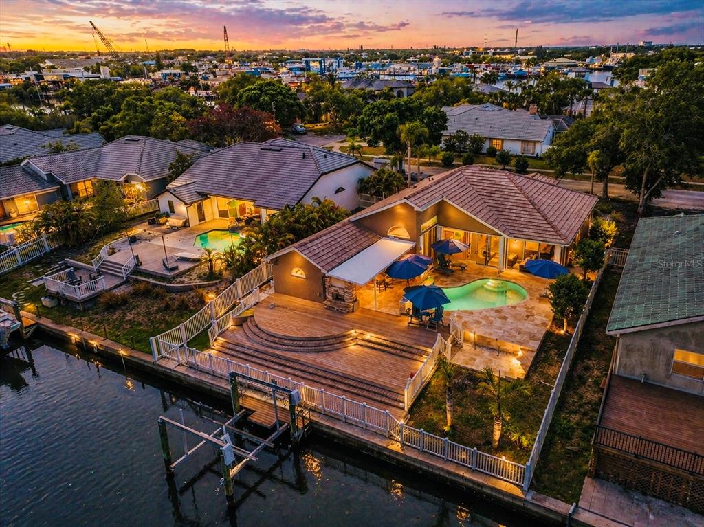 An aerial view of two waterfront houses with pools, wooden decks, and private boat docks — 1114 MARINA DRIVE, TARPON SPRINGS, FL