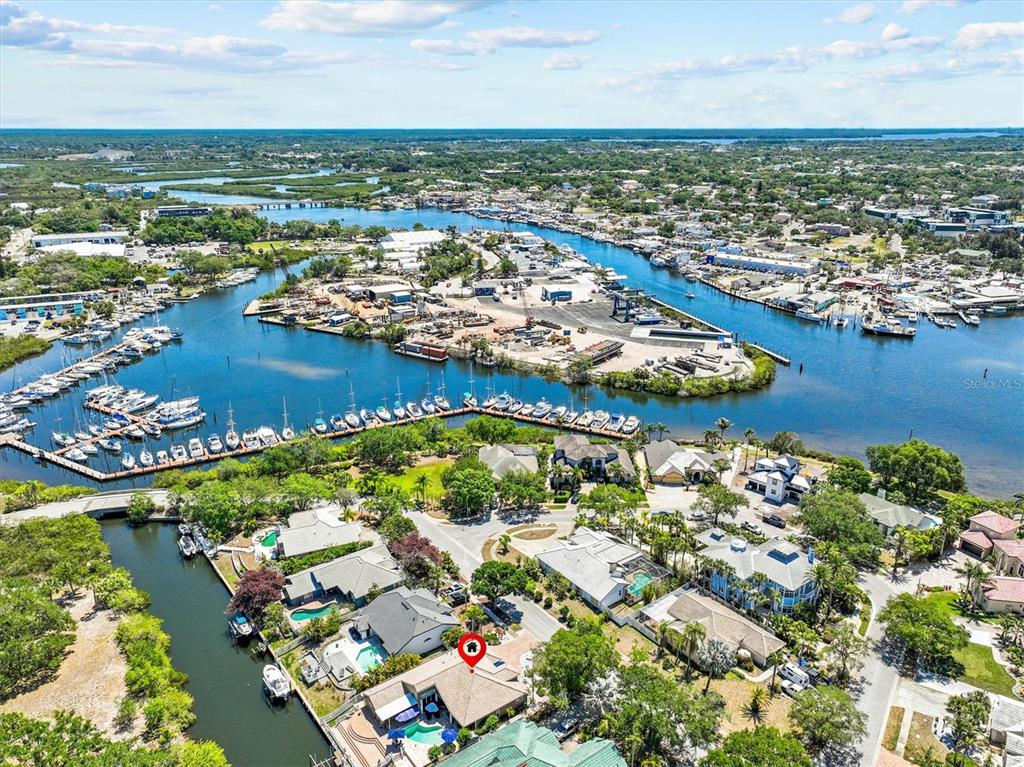 An aerial view shows a waterfront residential neighborhood with a canal, boat slips, and houses — 1114 MARINA DRIVE, TARPON SPRINGS, FL